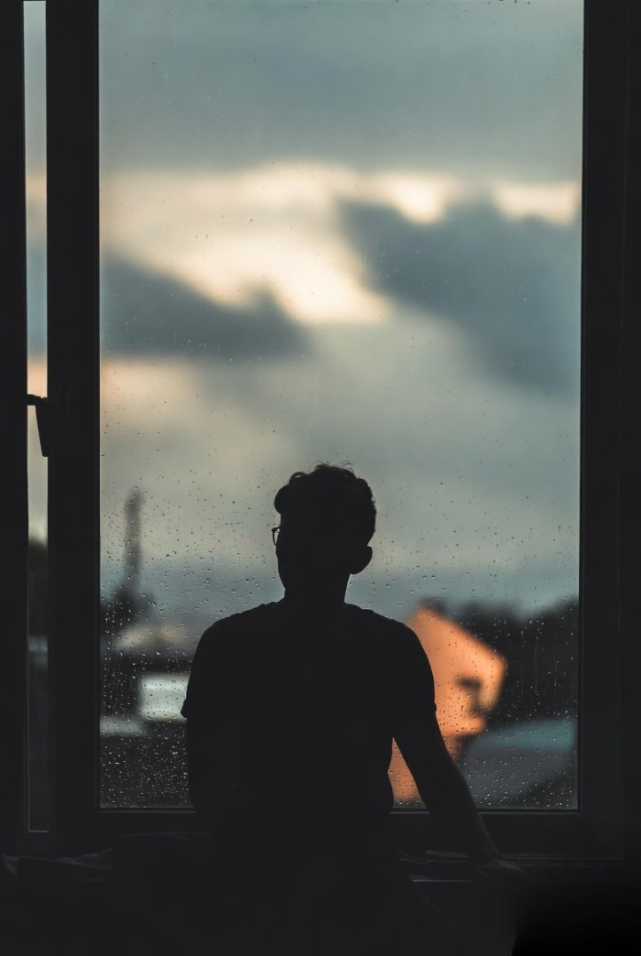person sitting by a window on a rainy day