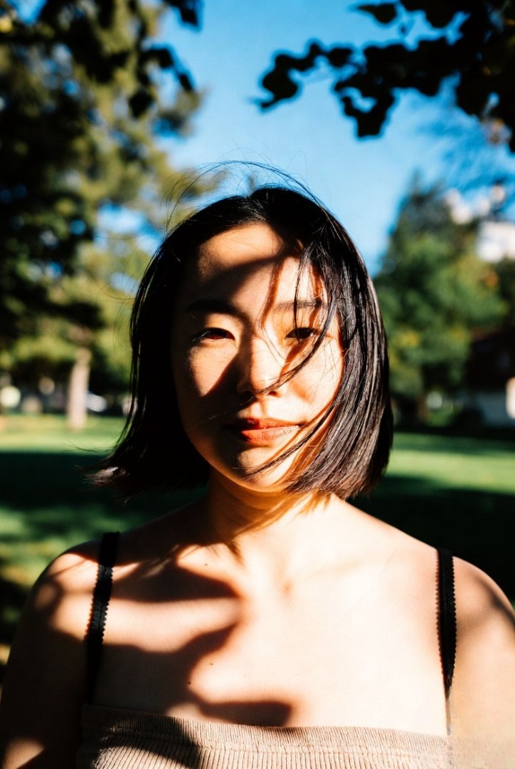 someone standing under sunlight, squinting slightly, wind in their hair. Natural, unposed, warm tones.
