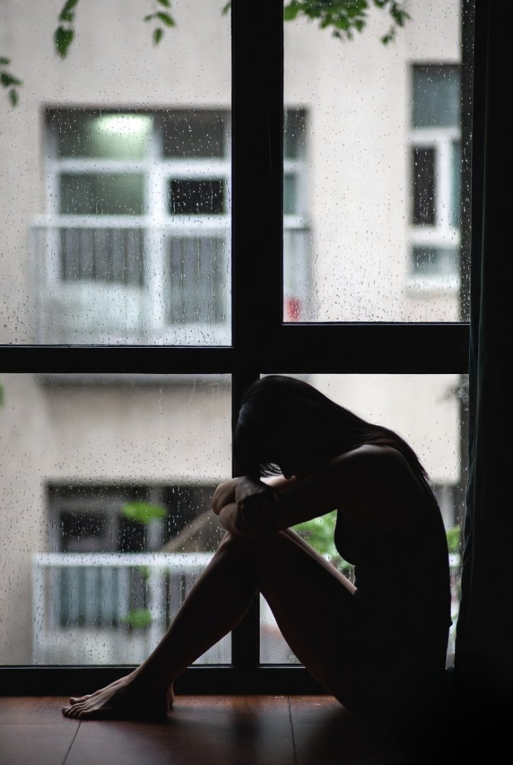 A person sitting quietly by a window during rain